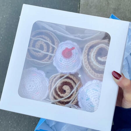 a box with a clear top showing crocheted cupcakes and cinnamon rolls