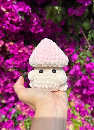crocheted mushroom with a milky white body and a pastel pink cap